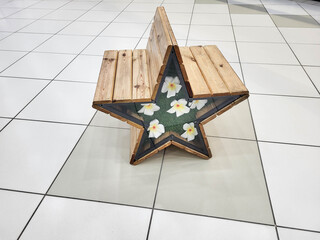 A star-shaped wooden bench filled with white artificial flowers.