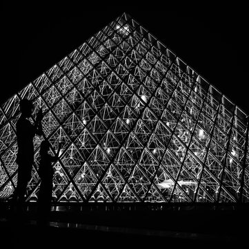 Paris, France: silhouette of tourists photographing the pyramid of the Louvre museum