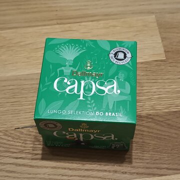 Dallmayr Capsa Lungo coffee capsules in green packaging on a wooden surface