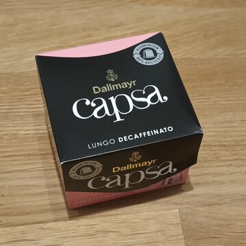 Dallmayr Capsa Lungo Decaffeinato coffee capsules packaging on a wooden surface