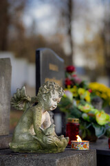Statue of an angel in a cemetery at evening with a burning candle.Memory of the deceased. Expression of love