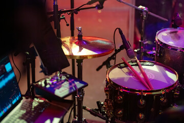 Professional drum kit with microphones and colored stage lighting in recording environment