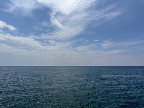 Open sea calm blue water and sky clouds.