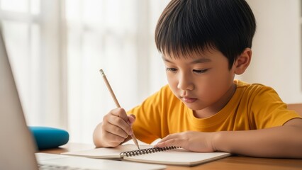 young boy focused on studying and writing in notebook at home during the daytime