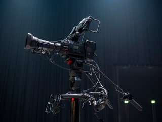 Professional video camera rig with accessories mounted on tripod against curtain