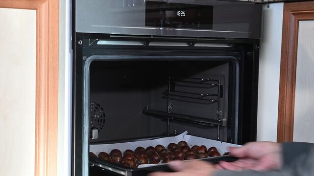The tray full of chestnuts is placed in the oven and the baking temperature is set. Making chestnut kebabs at home is an essential winter treat.