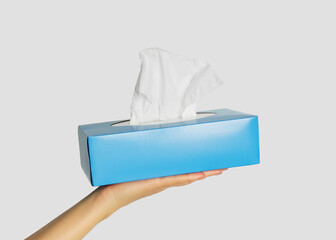 Hand holding a blue box of facial tissues