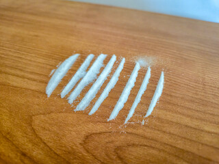 Lines of white powder on wooden table.