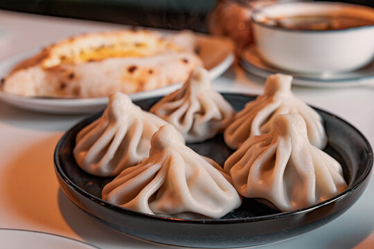Plate with khinkali dumplings, cheese khachapuri, and a bowl of soup, offering a traditional Georgian meal