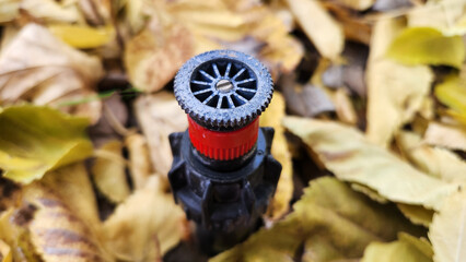 A spray irrigation sprinkler in a garden in the autumn