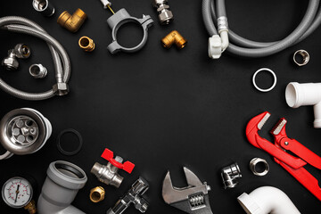 Plumbing tools and fittings on black background with copy space. Plumber equipment, flat lay