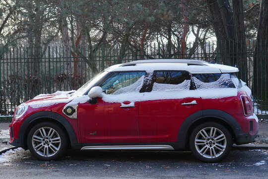 Bucharest, Romania &ndash; December 26, 2025: Closeup side view of BMW Mini Cooper Countryman red car parked along park fence in winter