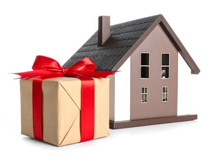 A miniature house sits alongside a wrapped gift box with a red ribbon. The composition is set against a white backdrop