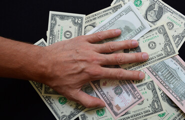 Paper US dollar bills covered by a man's hand. The fight against bribery, corruption, and fraud. Money for purchases, travel, loans. American currency during sanctions and crisis.