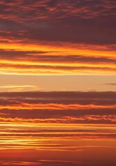Stunning vibrant dramatic sunset sky panorama featuring layered clouds bathed in intense warm golden and fiery reddish hues at twilight hour, evening, aerial, changing light
