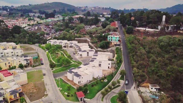 Aerial view of a residential area on the outskirts of the city, with repetitive housing and integrated natural surroundings.