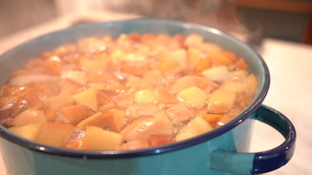 Chopped fruits simmering in a pot with steam rising, creating a traditional holiday beverage