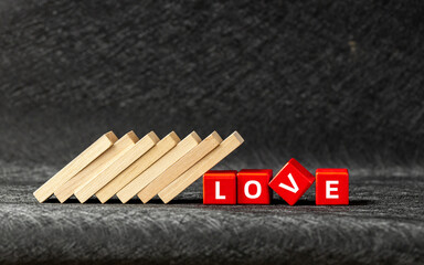  fall of love, collapse, the breakdown of feelings. The domino effect knocked over the red blocks with the word Love. concept of a falling apart relationship