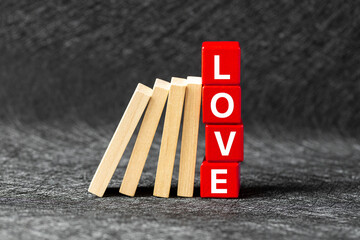 The domino effect tries to knock over the red blocks with the word love. The concept of emotional relationships. The end of love, a broken heart, collapse and falling apart.