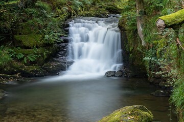Obraz premium Long exposure of the big waterfall on the Hoar Oak Water river at Watersmeet in Exmoor National Park