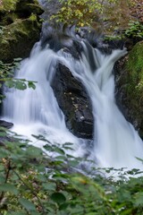 Fototapeta premium Long exposure of a waterfall on the East Lyn river flowing through the woods at Watersmeet in Exmoor National Park