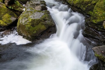 Fototapeta premium Long exposure of a waterfall on the East Lyn river flowing through the woods at Watersmeet in Exmoor National Park