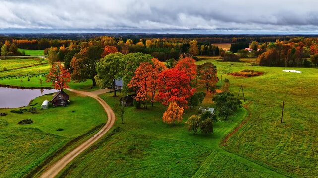 Drone video of autumn countryside with colorful trees and rural homes under cloudy sky