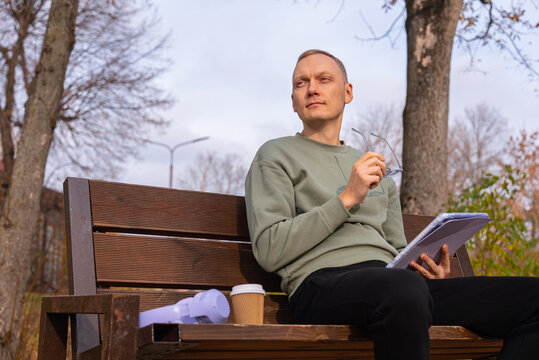 Reflective man sitting on a bench in autumn park