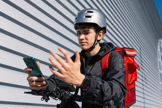 Young delivery boy on electric scooter using phone