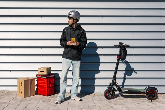 Young delivery boy with electric scooter outdoors