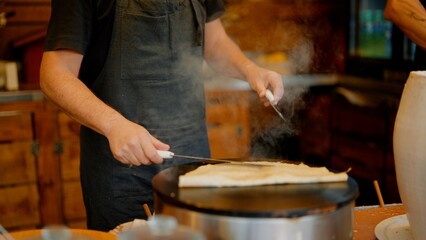 Using steady hands and spreader to shape batter into even circle