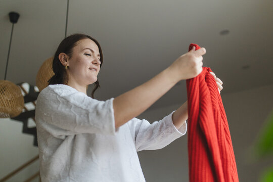 Woman holding a vibrant red sweater indoors