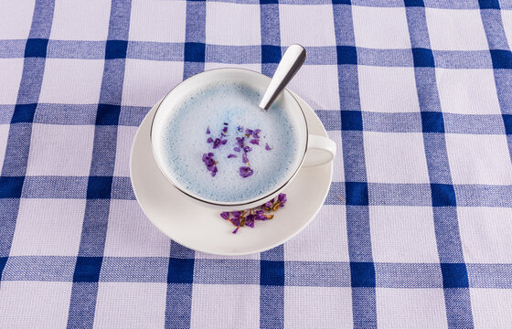 Blue matcha latte with floral garnish on checkered table