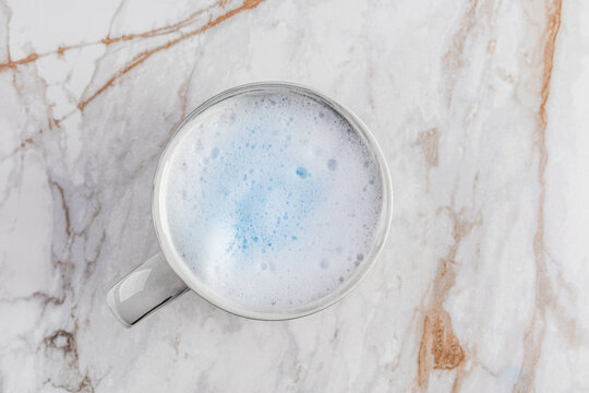 Frothy blue matcha latte resting on marble surface