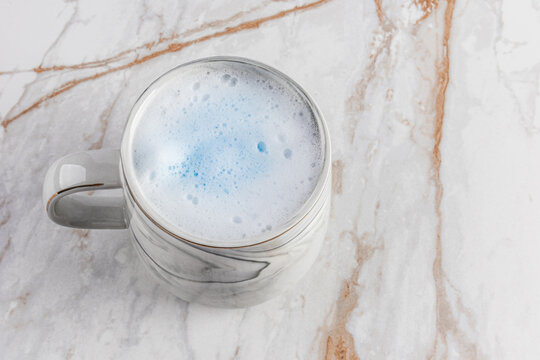 Blue matcha latte in a marble mug on marble table