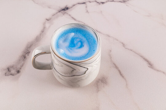Blue matcha latte in marble cup on marble surface
