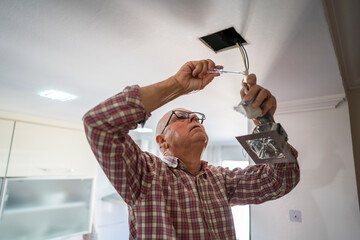 Senior renovating kitchen with DIY light installation