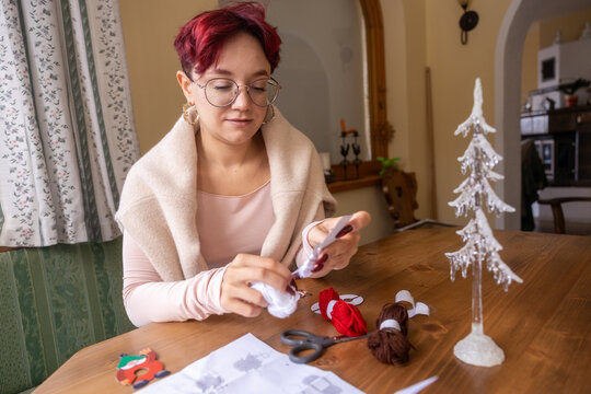 Young woman crafting at home with yarn and paper