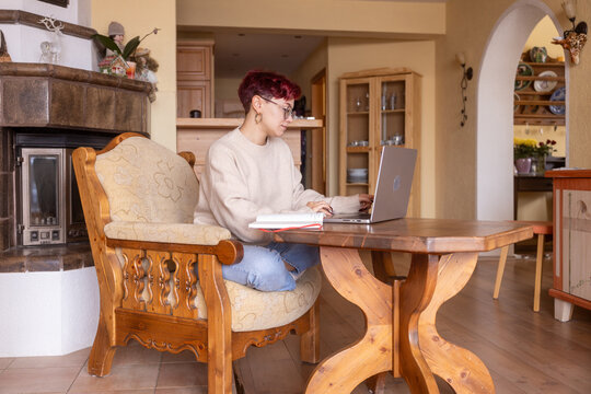 Young woman working on laptop at home wooden table
