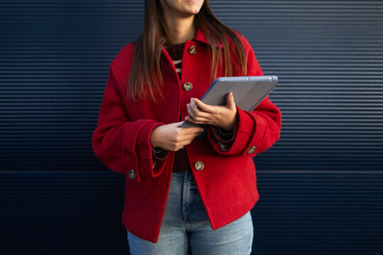 Woman in red coat holding tablet during winter