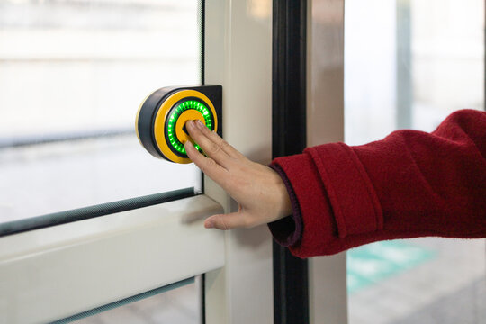 Woman in red coat presses button on a bus door