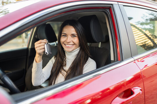 Woman smiling in car holding car keys, ready for journey