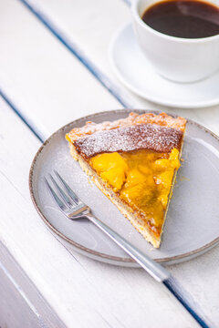 Mango cake slice with coffee on a white table