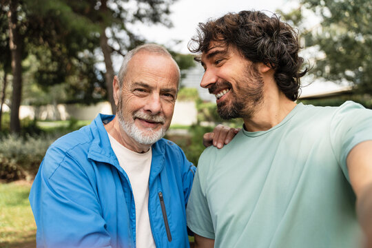 Happy senior man smiling at camera. Proud Father taking selfie in park with his son, after practicing sport bonding outdoors