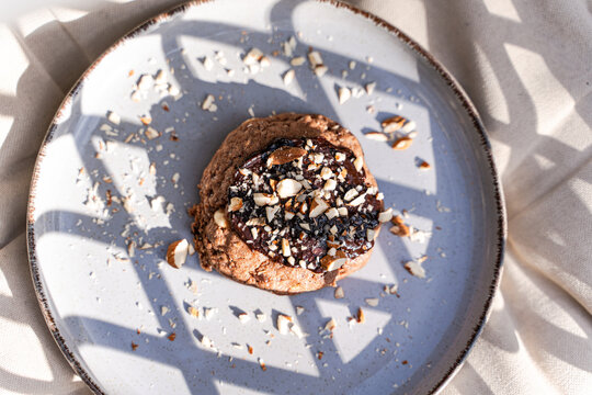 Chocolate cookie topped with nuts on a ceramic plate