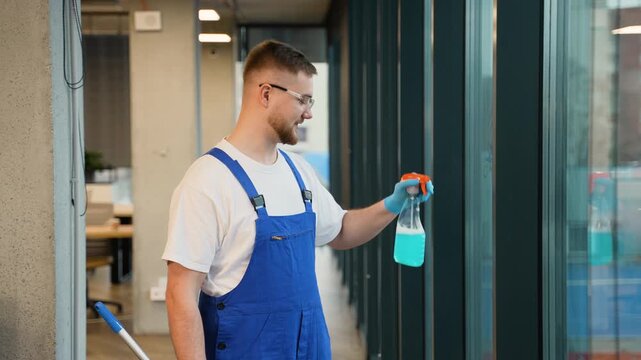 Professional janitor washing office windows with squeegee