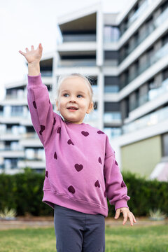 Toddler girl in pink sweater with heart pattern outside