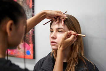 Makeup artist applying cosmetics to a model