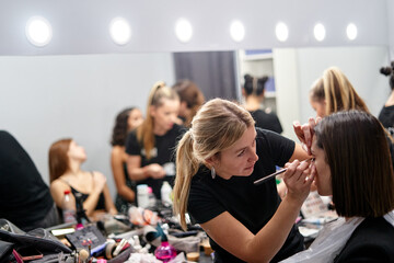 Makeup artist preps model during busy fashion photoshoot