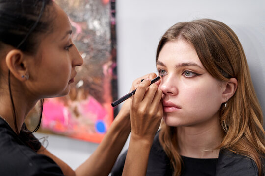 Makeup artist applying eyeliner to a young woman